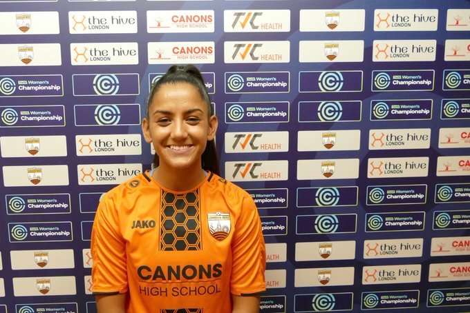 Rosie Kmita in front of Sponsors board after signing for London Bees