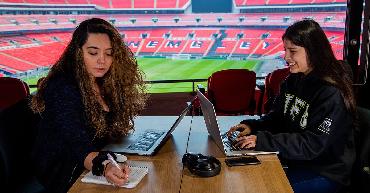 Two UCFB students studying overlooking Wembley Stadium Pitch