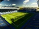 Aerial view of Stamford Bridge stadium with blue seats and green pitch bathed in golden afternoon light