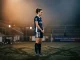 Female footballer in contemplative pose under dramatic lighting, representing pressure and scrutiny of fame