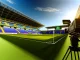 Empty WSL stadium on Saturday afternoon with broadcast camera facing unused pitch under bright daylight