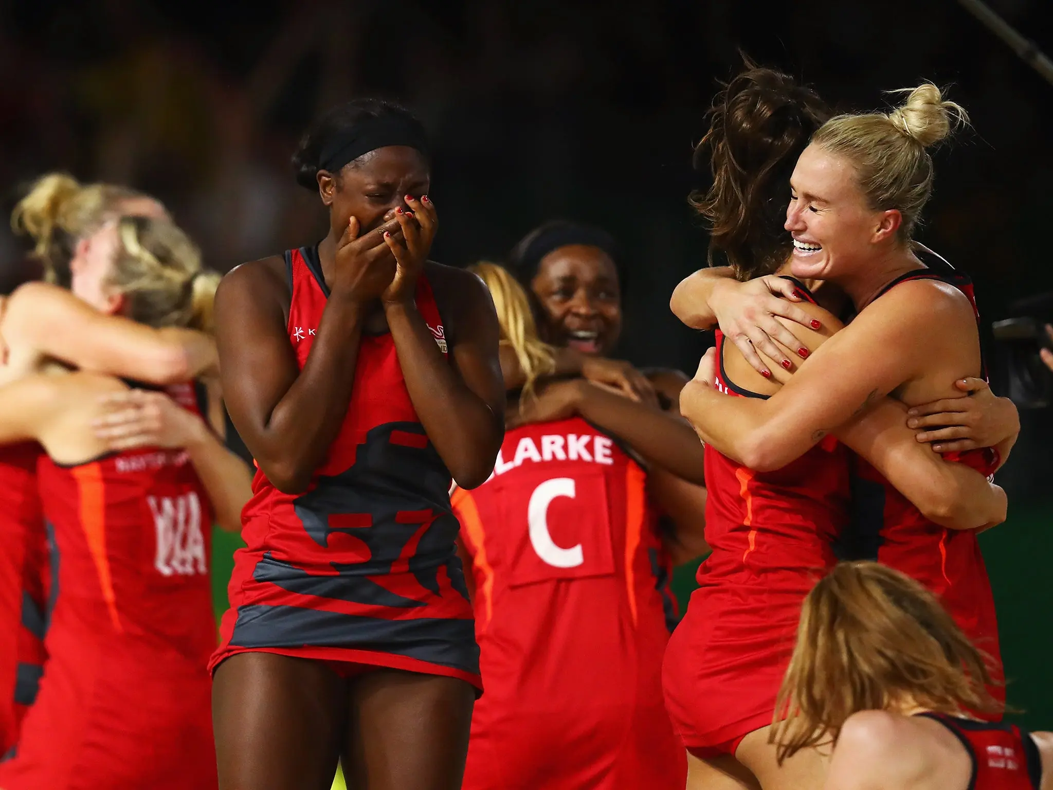 Team celebrates after a netball victory at the Commonwealth Games, showing joy and emotion.