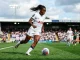 Female midfielder in Tottenham kit controlling football during WSL match