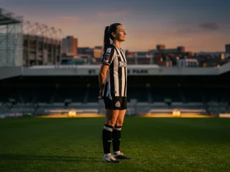 Newcastle United Women's defender in black and white striped kit on football pitch at sunset