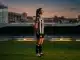 Newcastle United Women's defender in black and white striped kit on football pitch at sunset