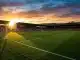 Empty Arsenal stadium at sunset with left side of pitch prominently featured in golden light