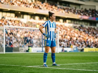 Brighton women's goalkeeper in blue and white kit standing in penalty area at stadium