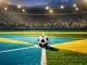 Floodlit football pitch with turquoise and gold geometric patterns, match ball on centre spot, packed stadium stands in shadow.