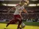 Female footballer in Lyon kit striking ball in stadium, dynamic midfield action shot