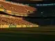 Empty floodlit stadium at golden hour with packed stands and dramatic lighting, no players visible.