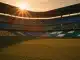 Floodlit stadium at golden hour with packed stands in DR Congo and Uzbekistan national colours, dramatic shadows on grass pitch.