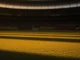 Empty floodlit football stadium at dusk with yellow, blue, black and red atmospheric lighting reflecting national colours.