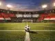 Egyptian flag-coloured stadium sections frame a floodlit pitch with a football on the centre spot, dramatic evening lighting.
