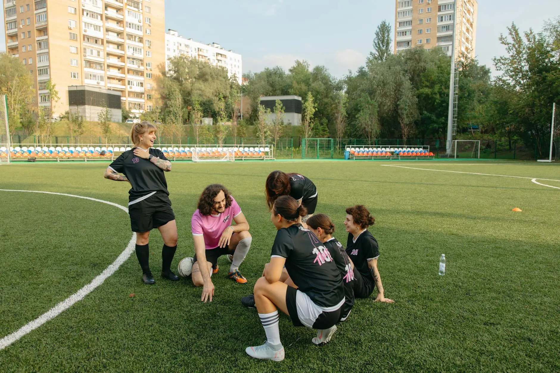 Female soccer players in training on a football pitch, laughing and interacting.