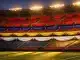 Floodlit stadium stands with Group C national flag colours in bunting, golden evening light, anticipatory pre-match atmosphere.