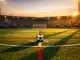 Floodlit football pitch at dusk with ball on centre spot, Haiti and Scotland colours reflected in dramatic shadows and turf.