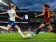 England and Spain women's footballers competing for the ball in dramatic stadium lighting