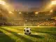Floodlit football pitch at dusk with ball on penalty spot, dramatic shadow patterns, stadium in anticipation mode.