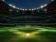 Floodlit stadium at dusk with ball on centre spot, emerald and red atmospheric lighting, packed stands in shadow.