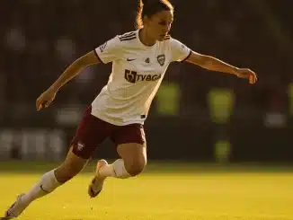 Female footballer in defensive action on pitch showing athletic positioning and tactical awareness