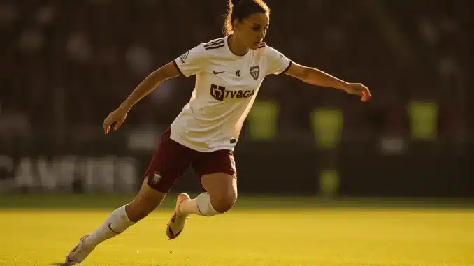 Female footballer in defensive action on pitch showing athletic positioning and tactical awareness
