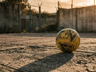 Football on cracked ground with dramatic shadows symbolizing detained athlete and human rights concerns