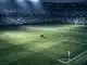 Floodlit stadium at night with blue and white lighting on the pitch, packed stands, and a football at centre circle.