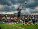 Women's Gaelic football player leaping for ball during TG4 All-Ireland Championship match in Irish stadium
