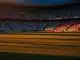 Floodlit World Cup 2026 quarter-final stadium with Argentina and Switzerland supporter sections under golden-hour lighting.