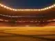 Empty floodlit stadium quarter-final pitch at dusk with packed stands, dramatic golden-hour lighting and shadow patterns.