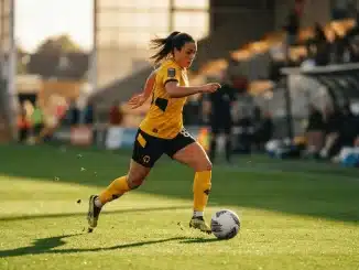 Women's footballer in yellow kit controlling ball in dynamic midfield action on professional pitch