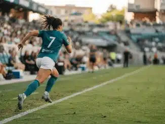 Women's soccer player in Bay FC kit running down the pitch during a match