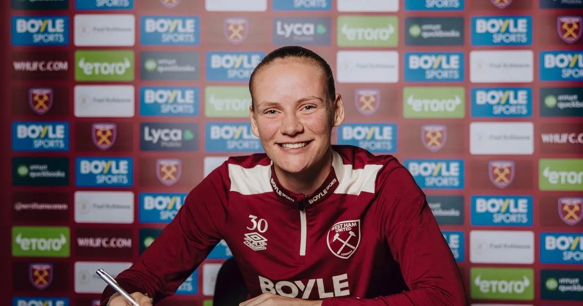 Katie O'Hanlon smiling in a West Ham United women's training kit during a signing event.