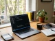 Modern workspace with laptop showing code, notebooks and coffee in natural light