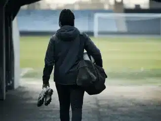 Female football defender walking toward a stadium pitch during a club transfer