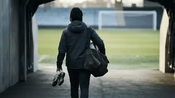 Female football defender walking toward a stadium pitch during a club transfer