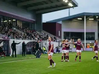 Women’s football match scene showing a tense substitution controversy at a stadium touchline
